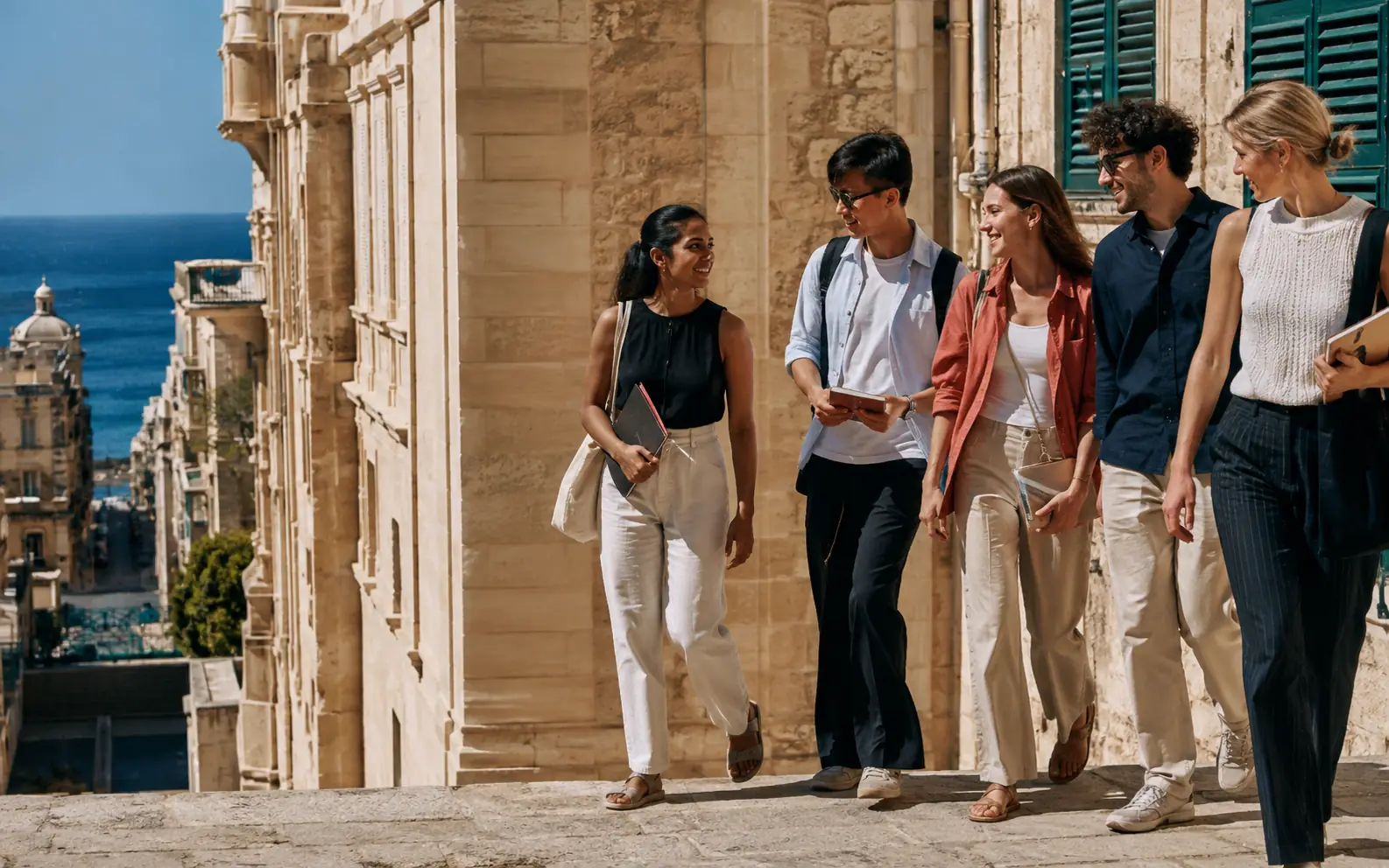 International students walking and talking on a sunlit street in Malta